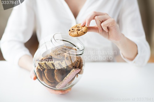 Image of close up of hands with chocolate cookies in jar