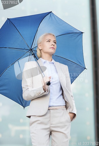 Image of young serious businesswoman with umbrella outdoors