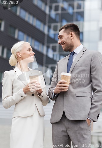 Image of smiling businessmen with paper cups outdoors