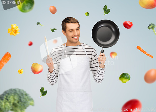 Image of happy man or cook in apron with pan and spoon
