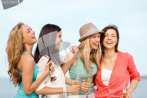 Image of smiling girls with drinks on the beach