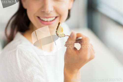 Image of close up of woman eating cake at cafe or home