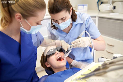 Image of female dentists treating patient girl teeth