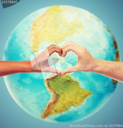 Image of human hands showing heart shape over earth globe