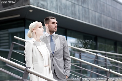 Image of serious businessmen standing over office building