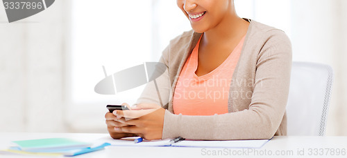 Image of african woman with smartphone in office
