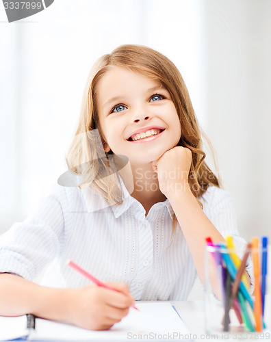 Image of smiling little student girl drawing at school