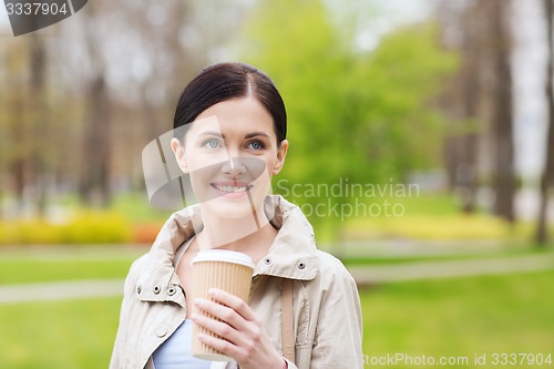 Image of smiling woman drinking coffee in park