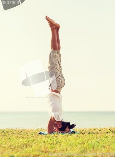 Image of man making yoga exercises outdoors
