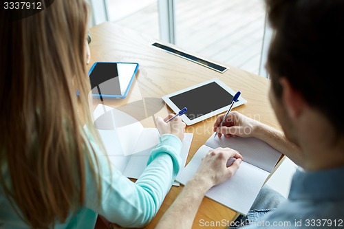 Image of students with tablet pc writing to notebooks