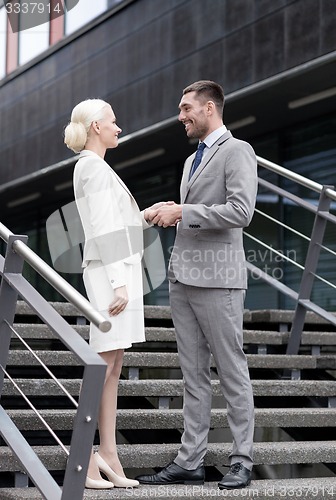 Image of smiling businessmen shaking hands on street