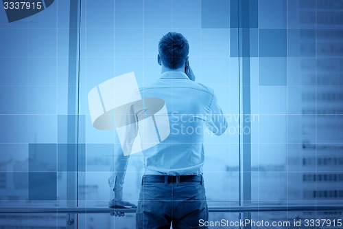 Image of businessman calling on smartphone in office