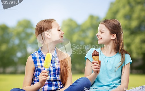 Image of happy little girls eating ice-cream in summer park