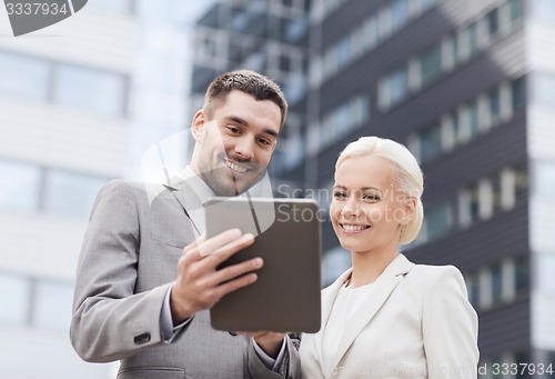 Image of smiling businessmen with tablet pc outdoors