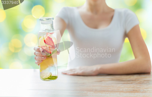 Image of close up of woman with fruit water in glass bottle