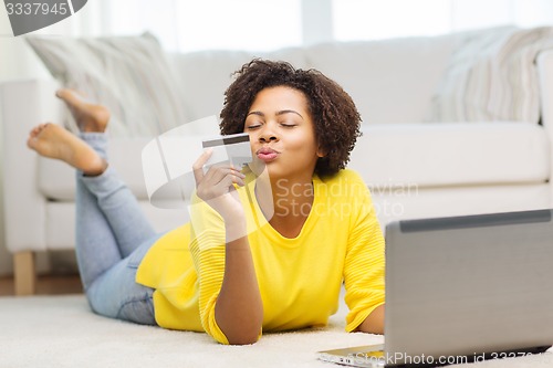 Image of happy african woman with laptop and credit card