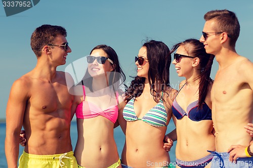 Image of smiling friends in sunglasses on summer beach