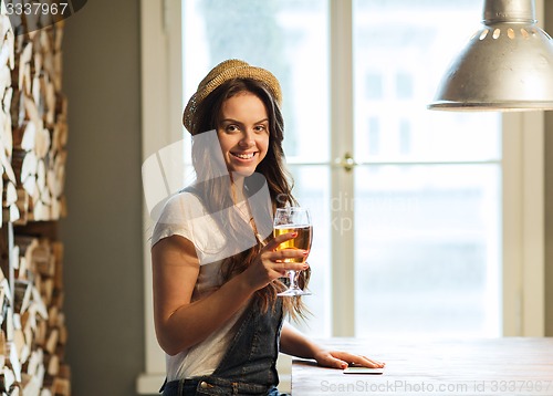 Image of happy young woman drinking beer at bar or pub