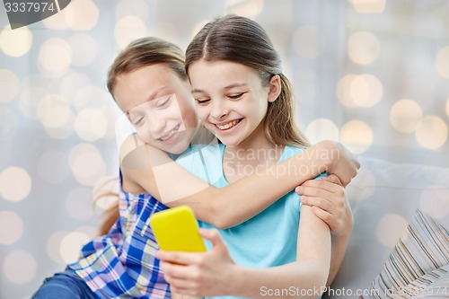 Image of happy girls with smartphone taking selfie at home