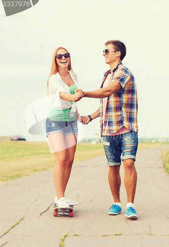 Image of smiling couple with skateboard outdoors