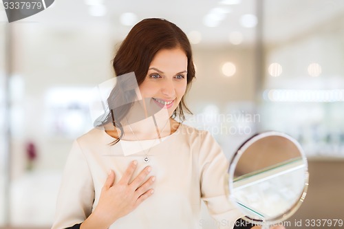 Image of happy woman choosing pendant at jewelry store