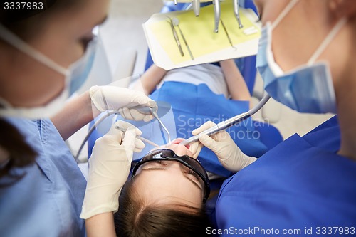 Image of female dentists treating patient girl teeth