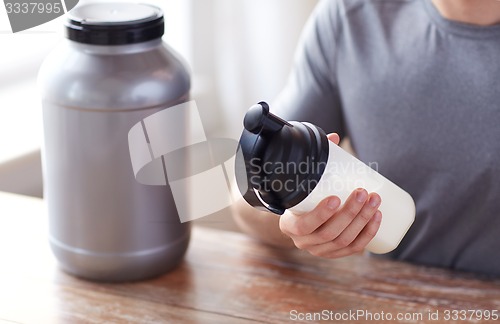 Image of close up of man with protein shake bottle and jar