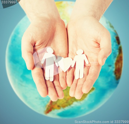 Image of male hands with paper gay couple figures and globe