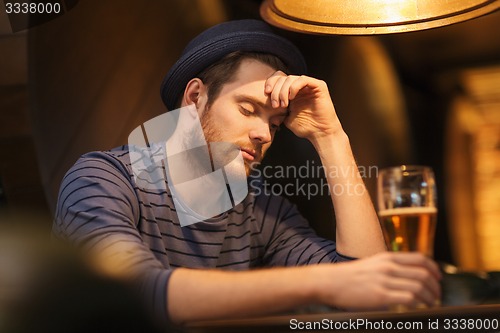 Image of unhappy lonely man drinking beer at bar or pub