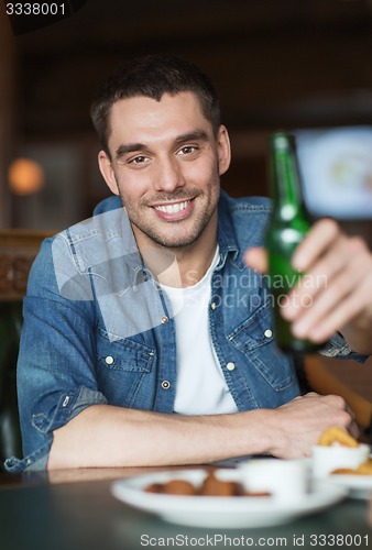 Image of happy young man drinking beer at bar or pub