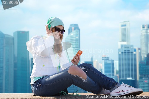 Image of happy young woman with smartphone and headphones