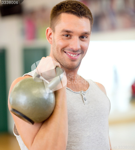 Image of smiling man with kettlebell in gym