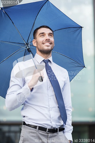 Image of young smiling businessman with umbrella outdoors