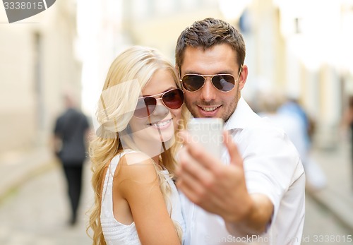 Image of smiling couple with smartphone in the city