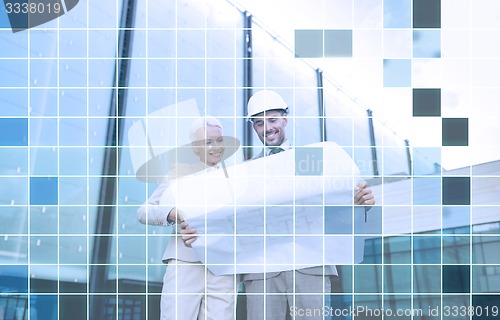 Image of smiling business people in helmets with blueprint