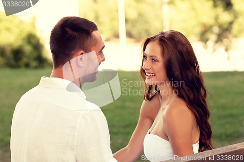 Image of smiling couple sitting on bench in park