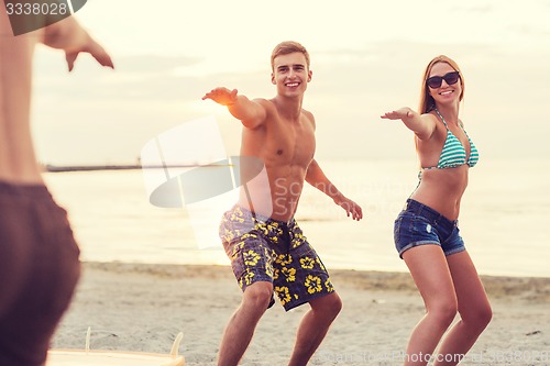 Image of smiling friends in sunglasses with surfs on beach