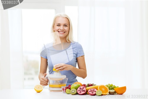 Image of smiling woman squeezing fruit juice at home
