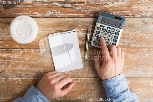 Image of close up of hands with calculator and notebook