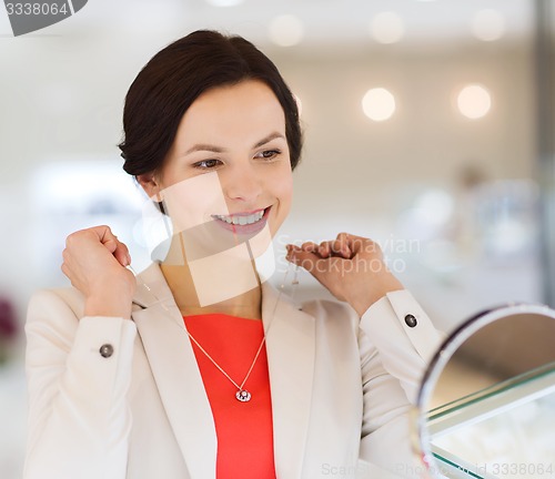 Image of happy woman choosing pendant at jewelry store