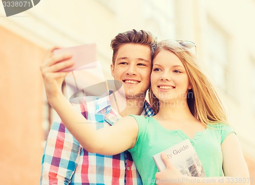 Image of smiling couple with smartphone in city