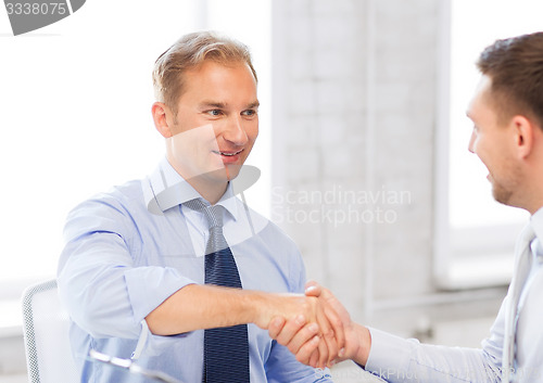 Image of businessmen shaking hands in office