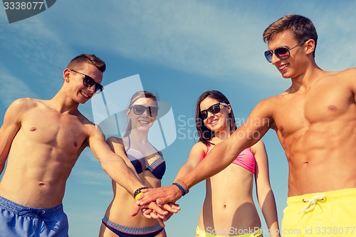Image of smiling friends with hand on top outdoors