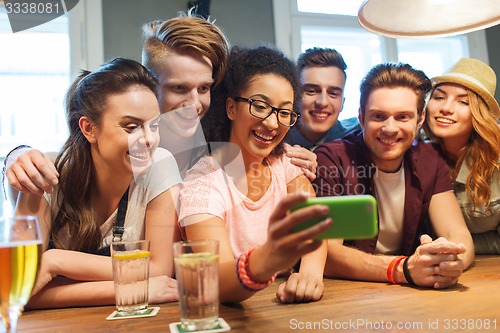 Image of happy friends with smartphone taking selfie at bar