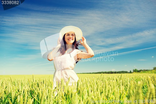 Image of smiling young woman in straw hat on cereal field