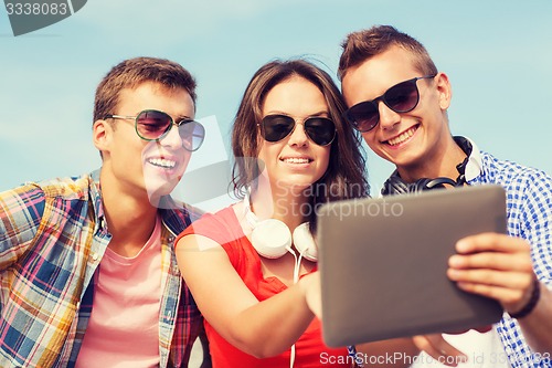 Image of group of smiling friends with tablet pc outdoors