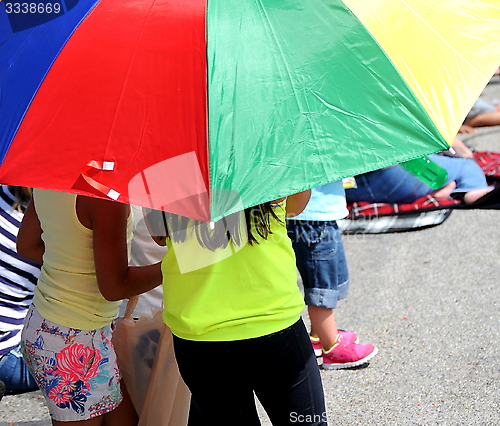 Image of Kids under umbrella.