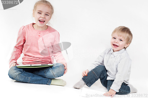 Image of Happy girl uses tablet and boy playing with chalk
