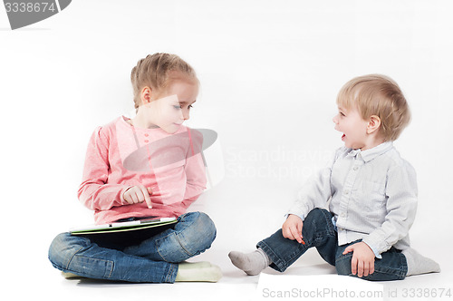 Image of Girl uses tablet and boy playing with chalk