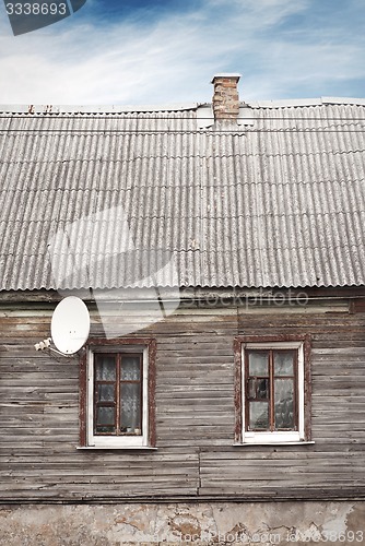 Image of old house with a tiled roof and chimney, dramatic blue sky background